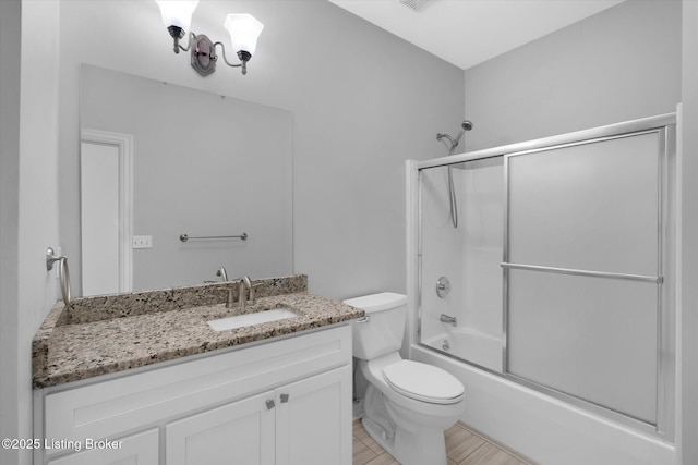 bathroom with toilet, shower / bath combination with glass door, and vanity