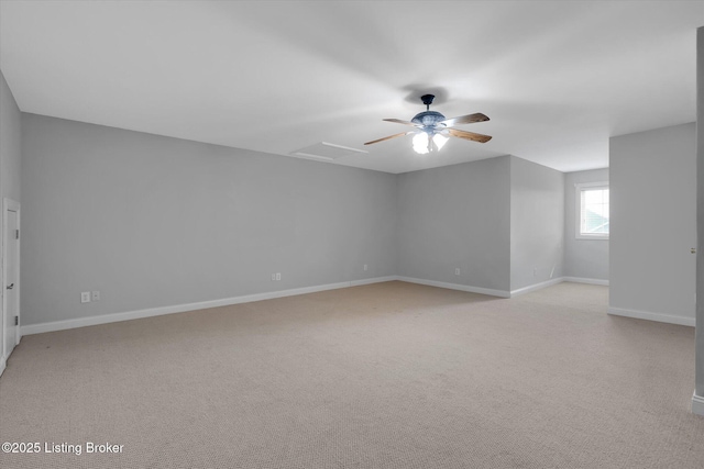 empty room with attic access, light colored carpet, ceiling fan, and baseboards