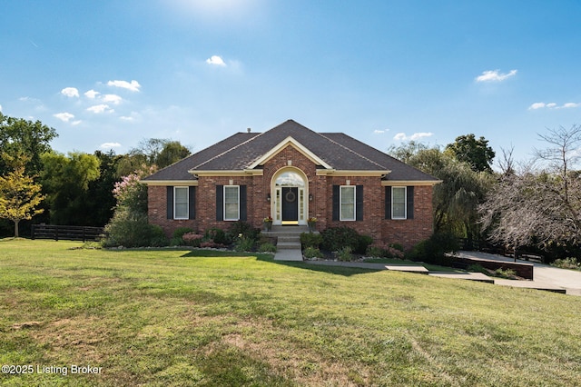 view of front facade with brick siding, a front yard, and fence