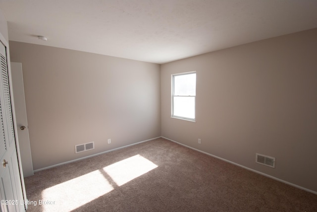 carpeted empty room with visible vents and baseboards