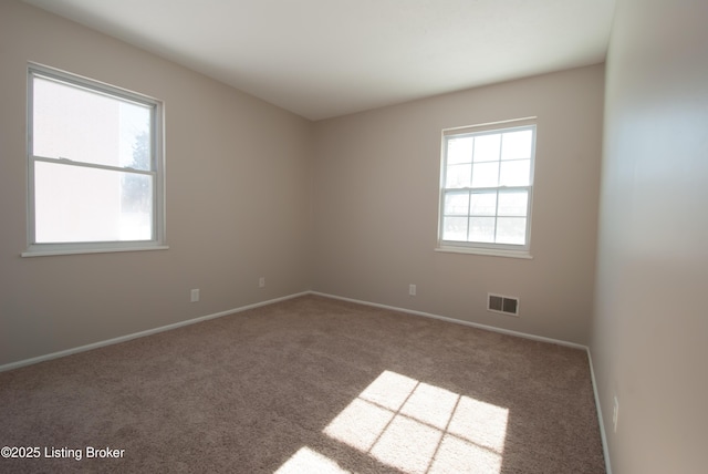 carpeted spare room featuring visible vents and baseboards