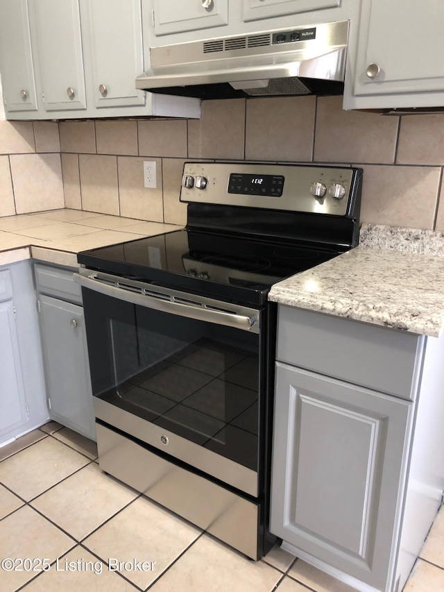 kitchen featuring tasteful backsplash, gray cabinets, light countertops, stainless steel range with electric cooktop, and under cabinet range hood