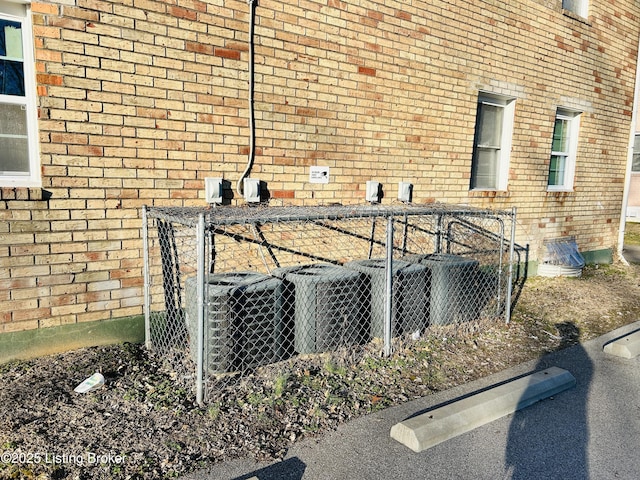 exterior details featuring central AC unit and brick siding