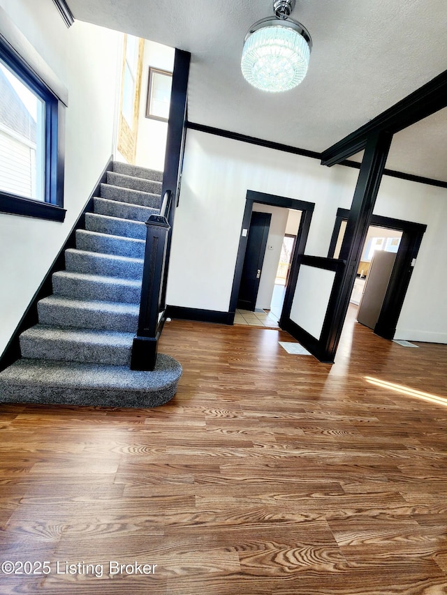 stairway with baseboards, ornamental molding, and wood finished floors