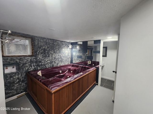 misc room featuring a jacuzzi, a textured ceiling, baseboards, and wallpapered walls