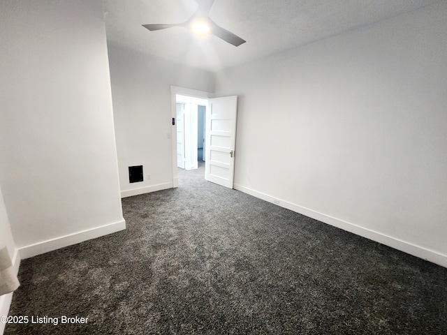 spare room with dark colored carpet, a ceiling fan, and baseboards