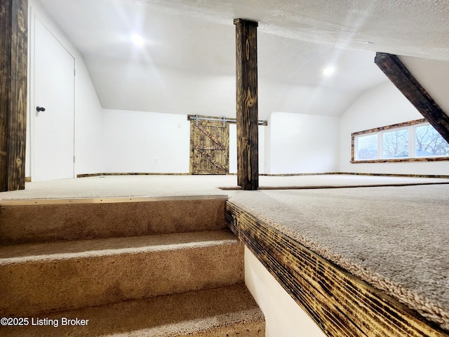 staircase with lofted ceiling, carpet flooring, and a textured ceiling