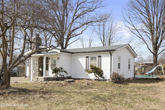 view of front facade featuring a shingled roof, a chimney, and a front lawn