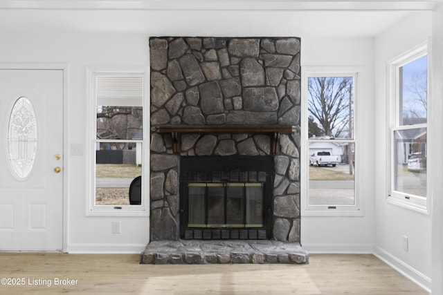 living room with baseboards, wood finished floors, and a stone fireplace