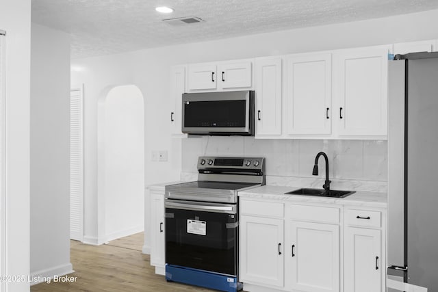 kitchen featuring appliances with stainless steel finishes, white cabinets, a sink, and visible vents