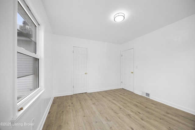 unfurnished room featuring baseboards, visible vents, and light wood finished floors