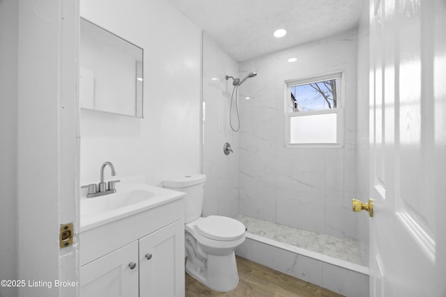 full bathroom with a textured ceiling, toilet, wood finished floors, vanity, and a marble finish shower