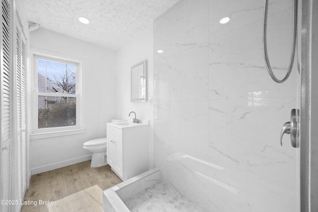 bathroom featuring a textured ceiling, toilet, wood finished floors, vanity, and walk in shower