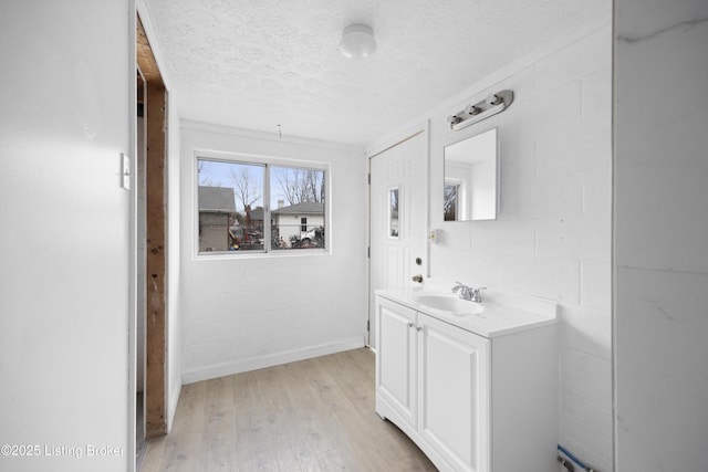 bathroom with concrete block wall, a textured ceiling, vanity, and wood finished floors