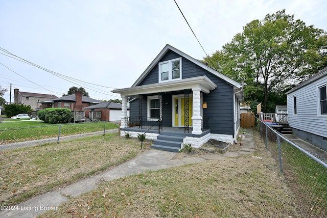 bungalow with a garage, covered porch, fence, and a front lawn