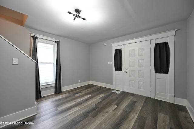 unfurnished bedroom with dark wood-style flooring, a closet, visible vents, and baseboards