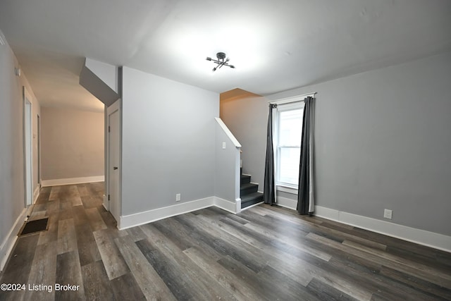 unfurnished room featuring dark wood-style floors, stairway, visible vents, and baseboards