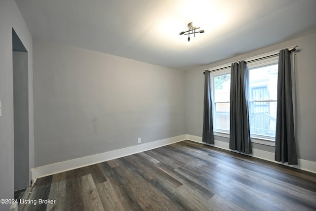 empty room with dark wood-type flooring and baseboards