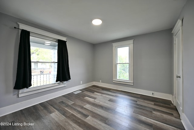 spare room with baseboards, visible vents, and dark wood finished floors