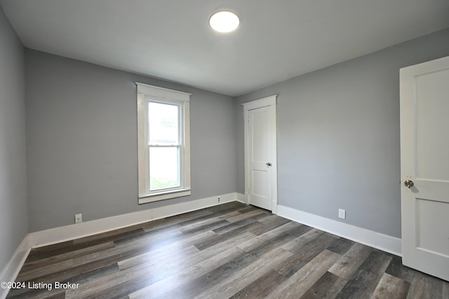 unfurnished room with dark wood finished floors and baseboards