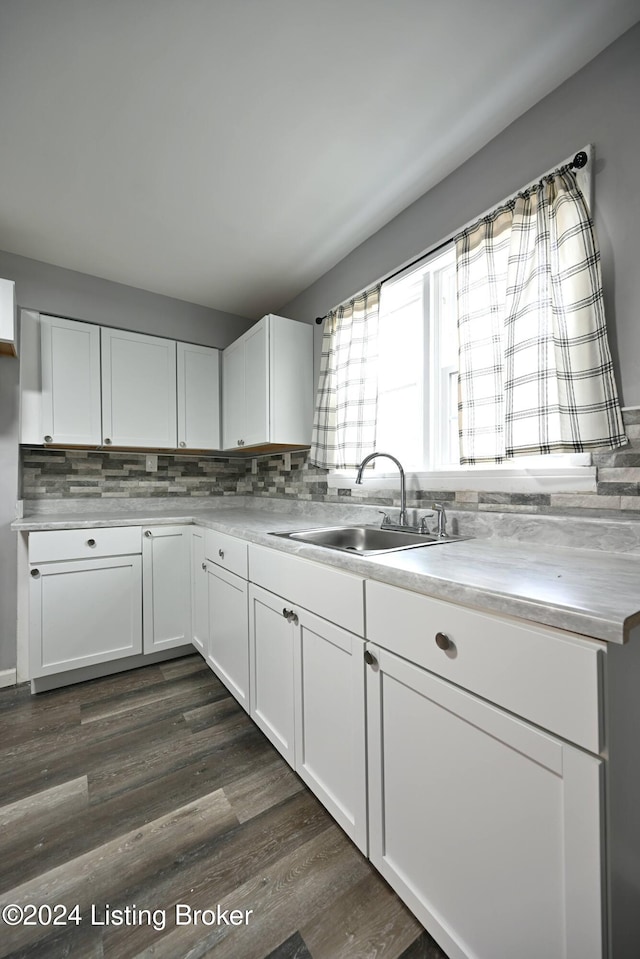 kitchen featuring dark wood-style flooring, light countertops, backsplash, white cabinets, and a sink