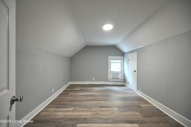 additional living space with vaulted ceiling, dark wood finished floors, and baseboards