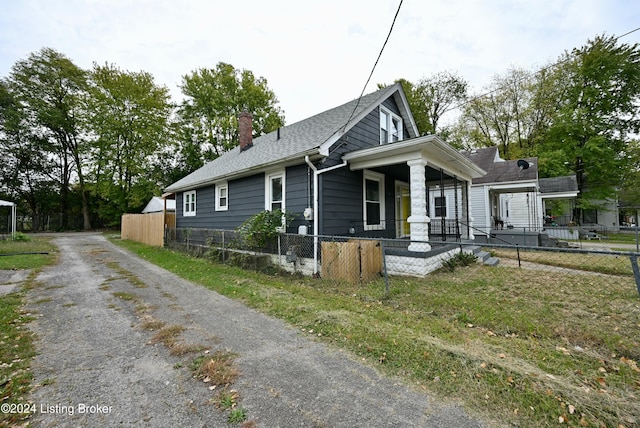 view of front facade with a fenced front yard, a chimney, a porch, and a shingled roof