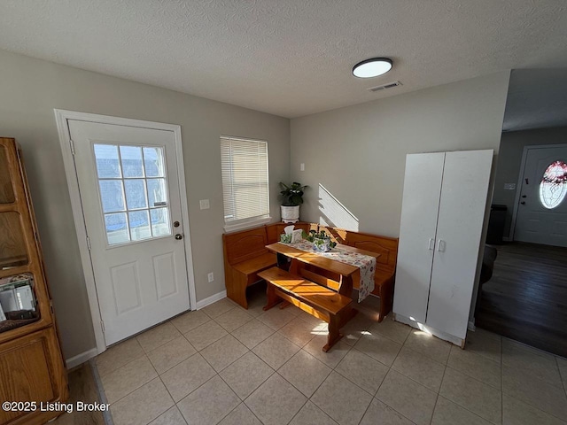 foyer entrance with visible vents, a textured ceiling, baseboards, and light tile patterned flooring