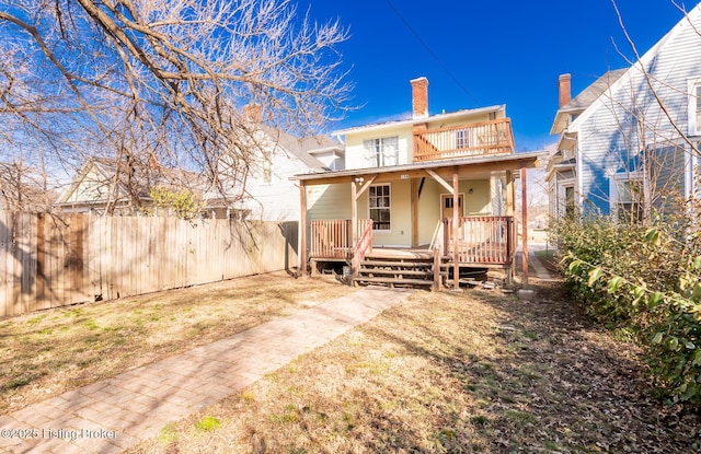 rear view of property featuring a porch, a chimney, fence, and a balcony