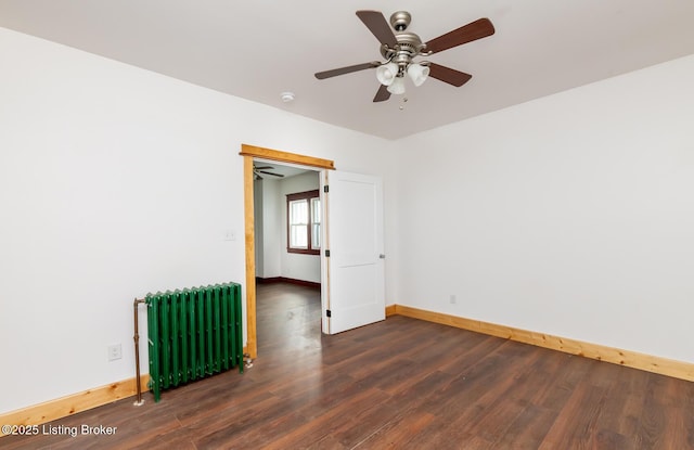 empty room featuring radiator, a ceiling fan, baseboards, and wood finished floors