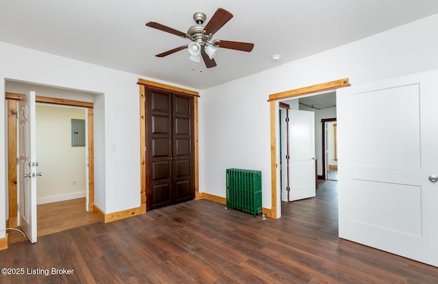 unfurnished bedroom with radiator heating unit, electric panel, baseboards, and dark wood-style flooring