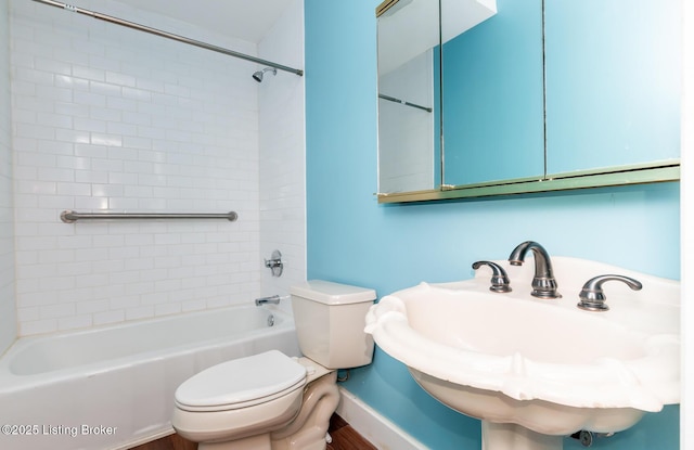 bathroom featuring toilet, shower / tub combination, and a sink