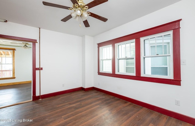 empty room featuring dark wood-type flooring, a ceiling fan, and baseboards