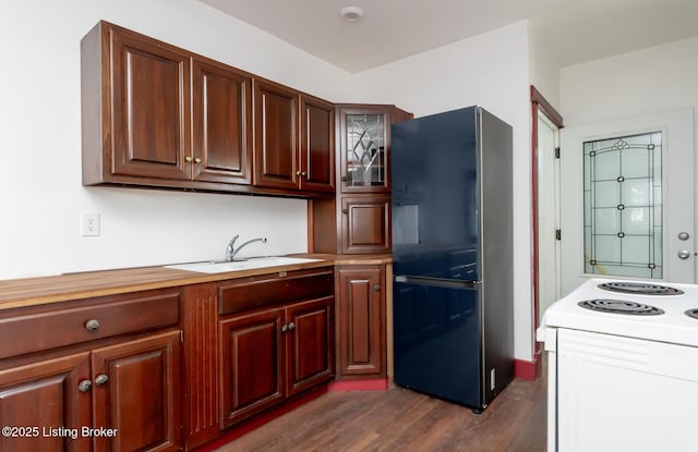 kitchen featuring dark wood-style flooring, light countertops, glass insert cabinets, freestanding refrigerator, and a sink