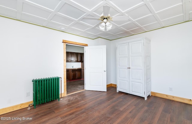 unfurnished bedroom featuring dark wood-style flooring, baseboards, a sink, and radiator heating unit