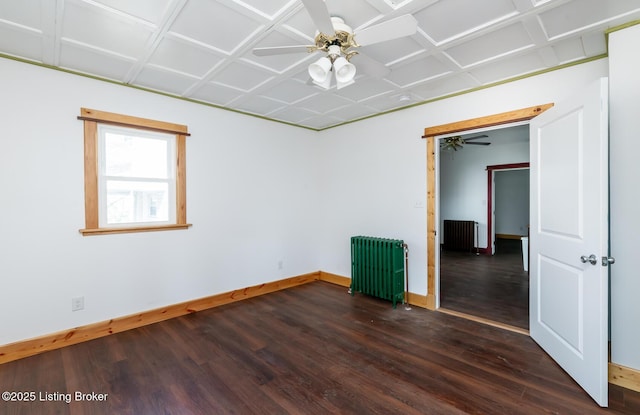 unfurnished room featuring a ceiling fan, radiator heating unit, baseboards, and dark wood-style flooring