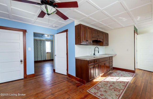 kitchen with dark wood-style floors, light countertops, a sink, ceiling fan, and baseboards