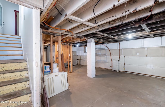 unfinished below grade area featuring radiator heating unit and stairway