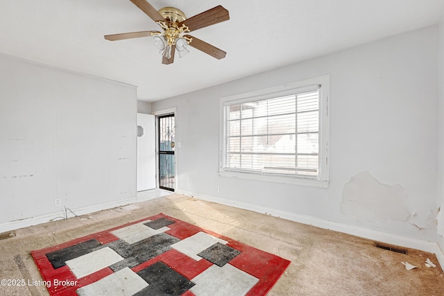 carpeted empty room with a ceiling fan, visible vents, and baseboards