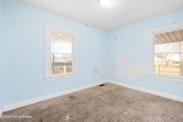 unfurnished room with baseboards, carpet flooring, visible vents, and a healthy amount of sunlight