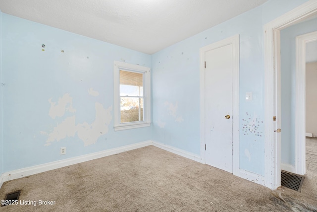 carpeted spare room featuring baseboards and visible vents