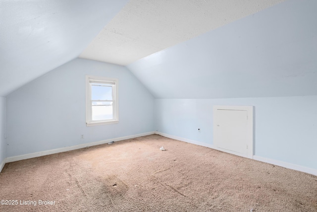 additional living space featuring carpet, vaulted ceiling, a textured ceiling, and baseboards