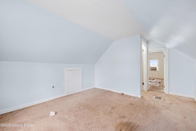 additional living space featuring baseboards, visible vents, vaulted ceiling, and carpet flooring