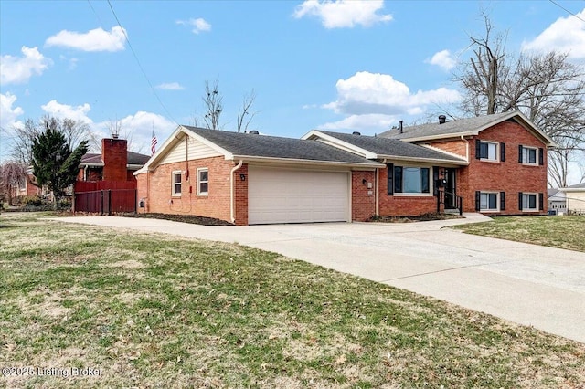 tri-level home featuring concrete driveway, brick siding, an attached garage, and a front yard