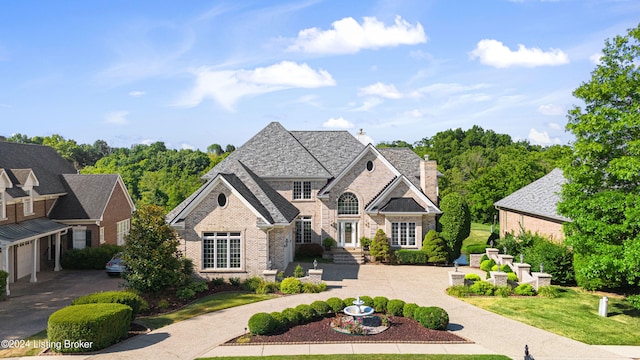 view of front of property with driveway, brick siding, a chimney, and a front yard