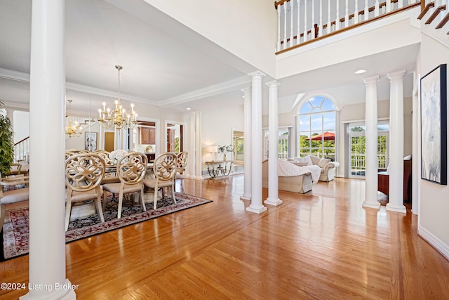 dining space with a high ceiling, wood finished floors, baseboards, ornamental molding, and ornate columns