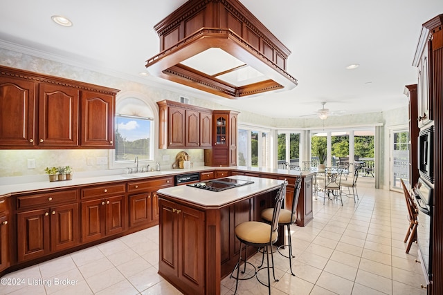 kitchen featuring a sink, black appliances, plenty of natural light, a peninsula, and a kitchen breakfast bar