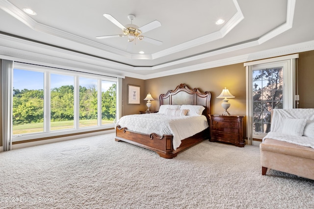 carpeted bedroom with ceiling fan, a tray ceiling, and crown molding