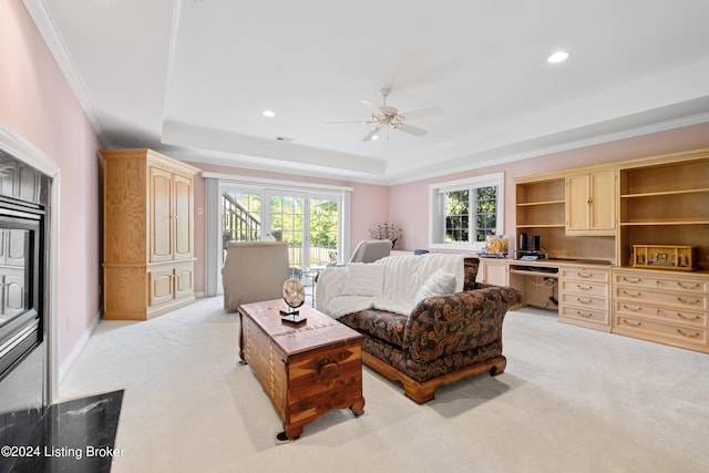 living area with a raised ceiling, crown molding, and light colored carpet