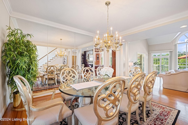 dining space featuring lofted ceiling, ornamental molding, wood finished floors, a chandelier, and ornate columns